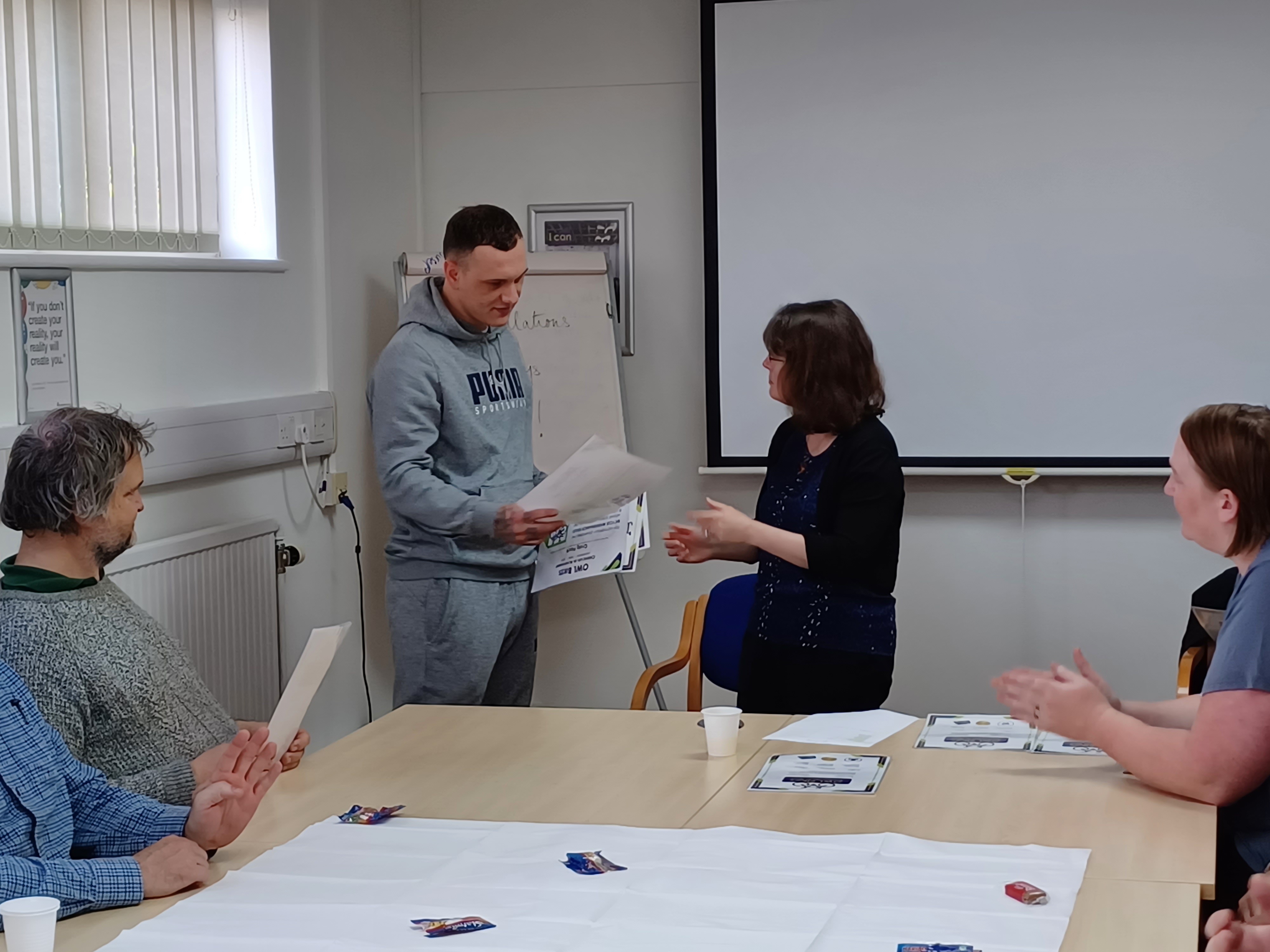 Image of a trustee giving a certificate to a participant