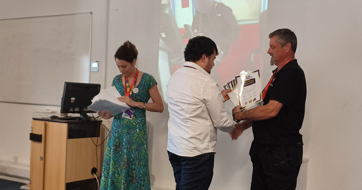 A photo of Fleur and Barry presenting a customer with a certificate.